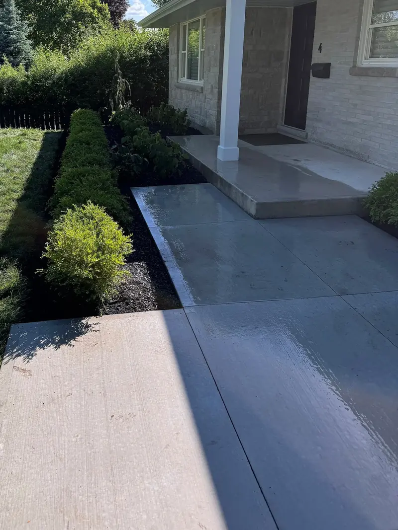 New concrete front walkway and porch lined with boxwood shrubs