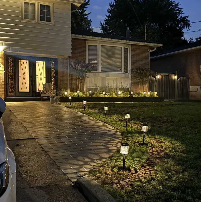 Curved paver walkway to a front door, lit at night with path lights