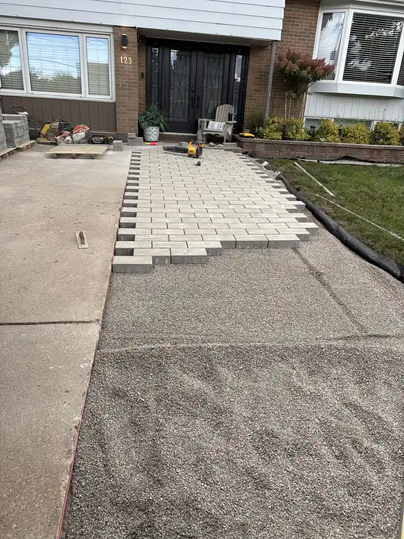 New pavers being laid over a compacted gravel base leading to a front door
