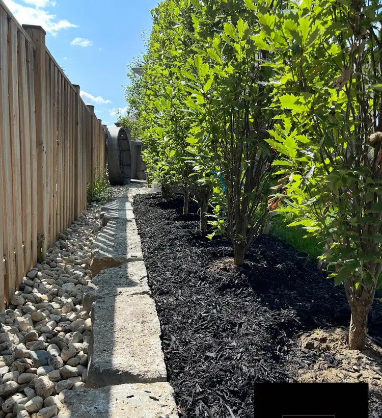 River rock drainage channel and mulched bed along a side yard